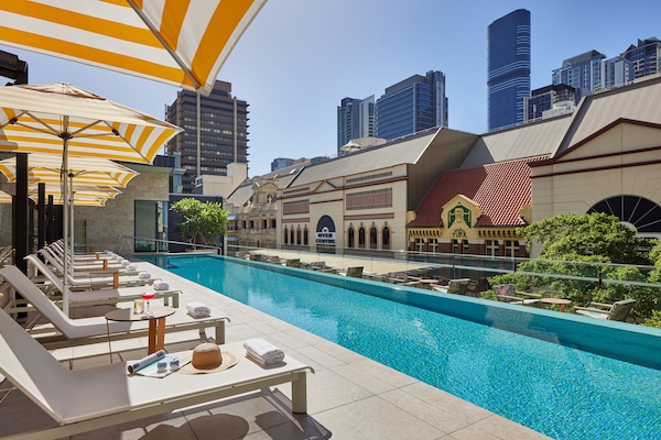 Una piscina al aire libre, sombrillas, sillones reclinables de piscina