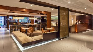 A modern hotel lobby with a bar area, seating, and a reception desk. - Hyatt Regency Brisbane (Brisbane)