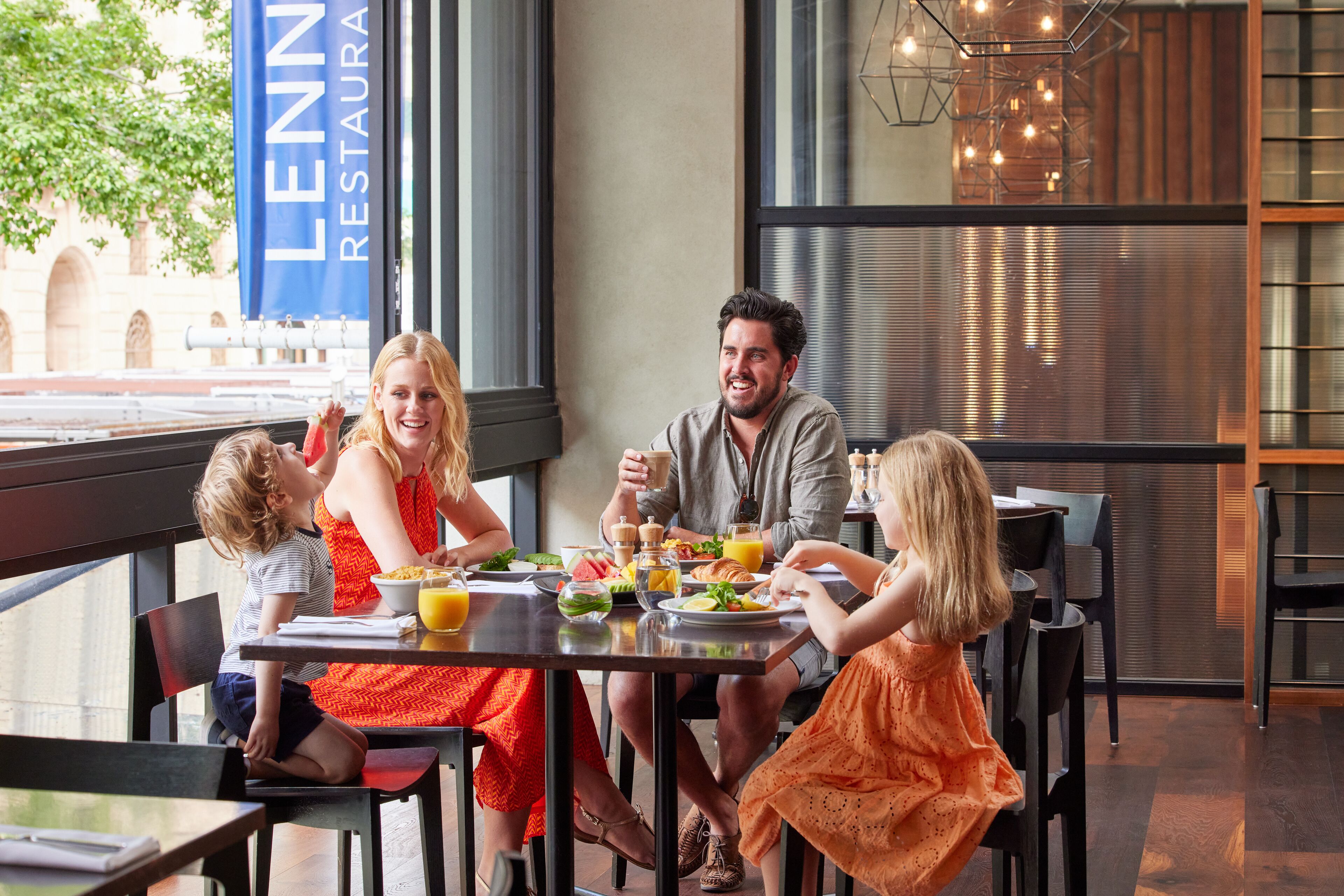 A family dining at a table in a restaurant with a view of the outside.