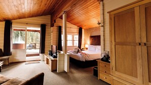 A log cabin room with a bed, desk, and a view of the outdoors.