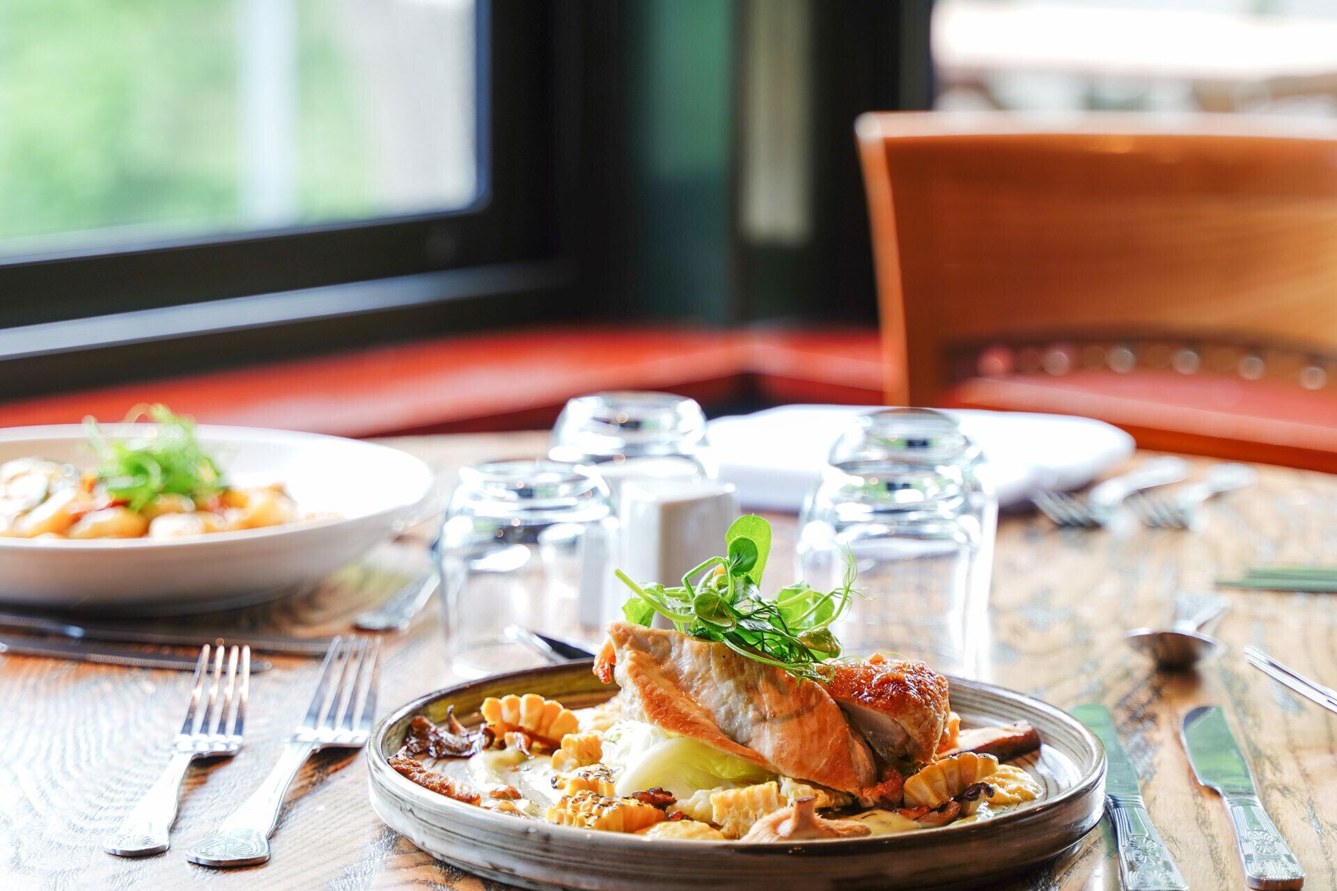 A dining table with plates of food, cutlery, and salt and pepper shakers.