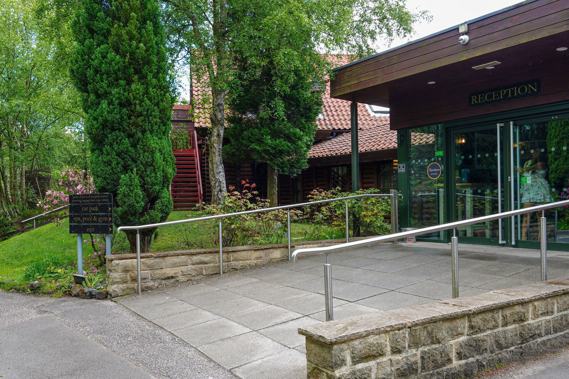 A reception area with a sign indicating directions to the car park, spa, pool & gym, and exit.