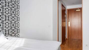 Un dormitorio con cama, pared de diseño geométrico y puerta de madera.