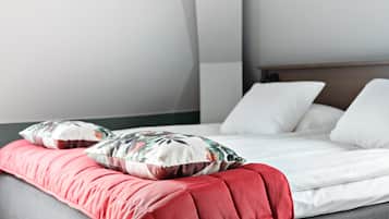A bed with white bedding and red pillows, a grey headboard, and a grey bench with red cushions.