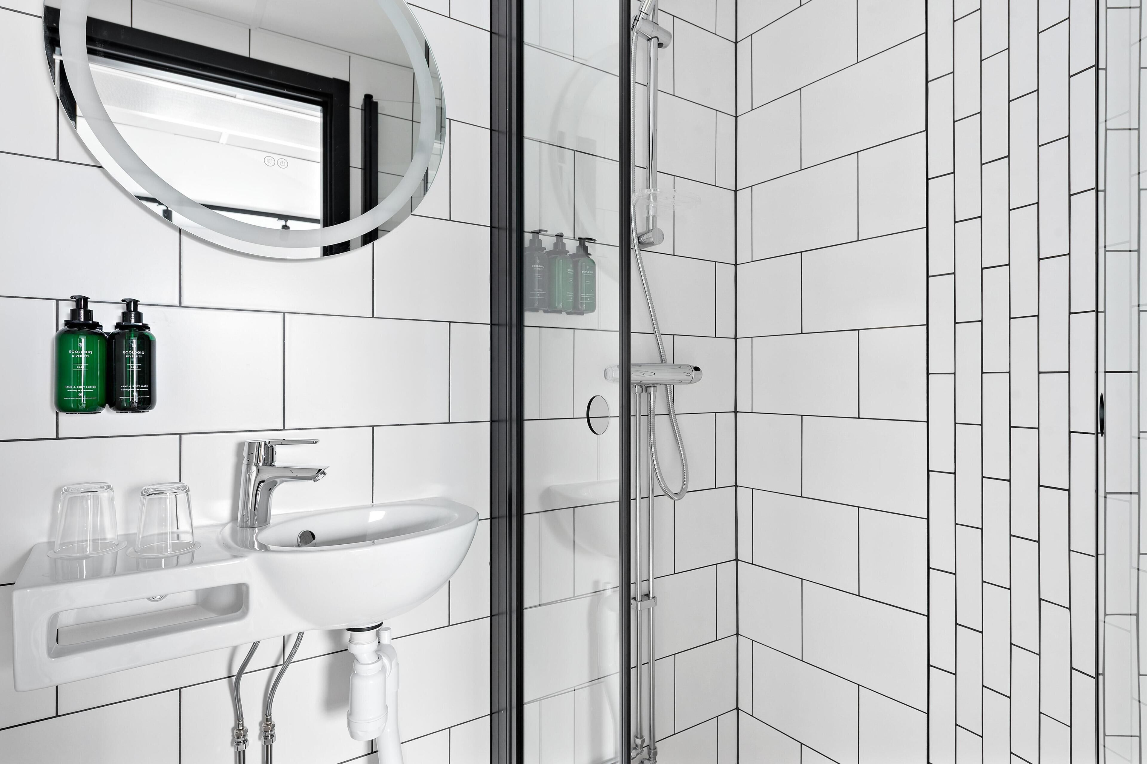 A bathroom with a white sink, mirror, and shower.