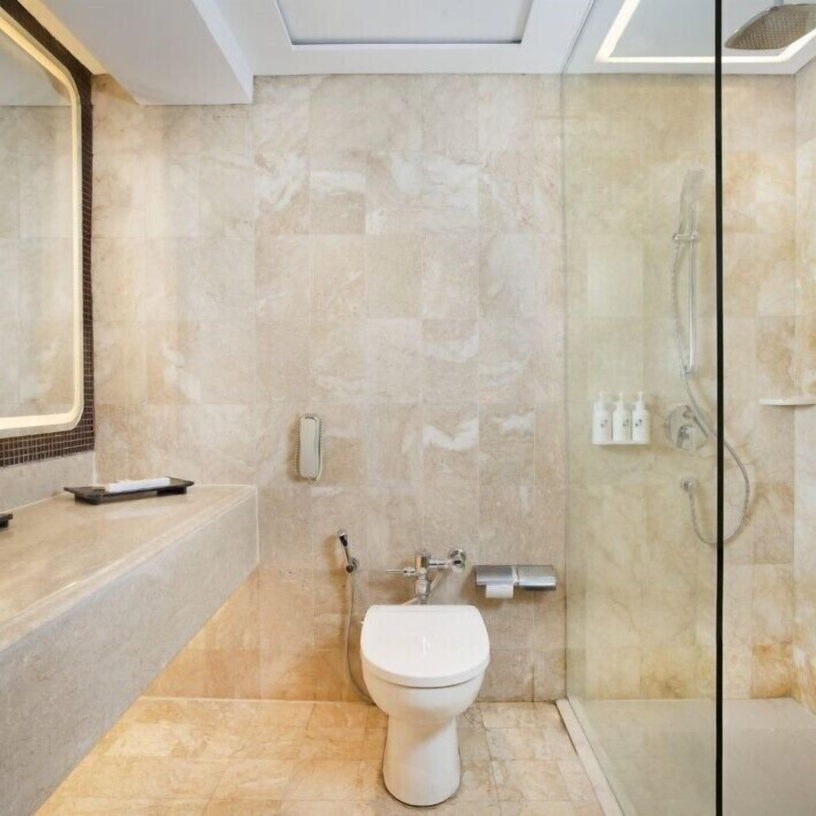 Un baño moderno con inodoro, ducha y tocador con espejo.