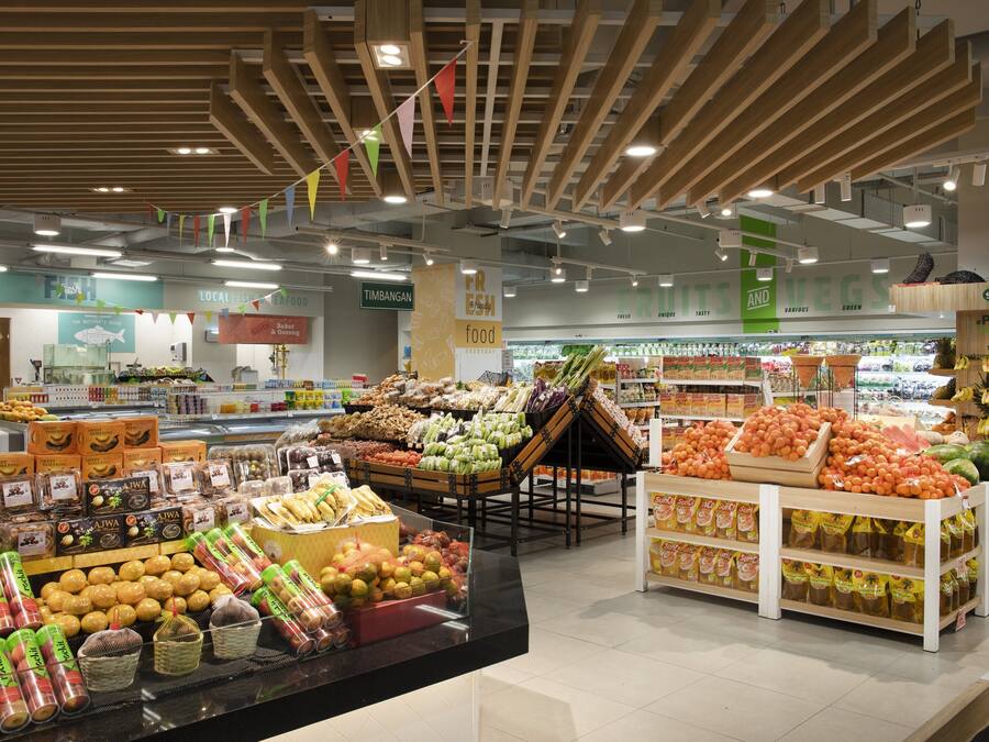 L’intérieur d’une épicerie, avec différents rayons proposant une variété de produits alimentaires, notamment des fruits et légumes frais et des produits emballés.