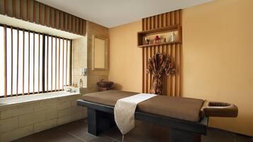Relax in a serene spa room with a large massage table, sink, and ample natural light.