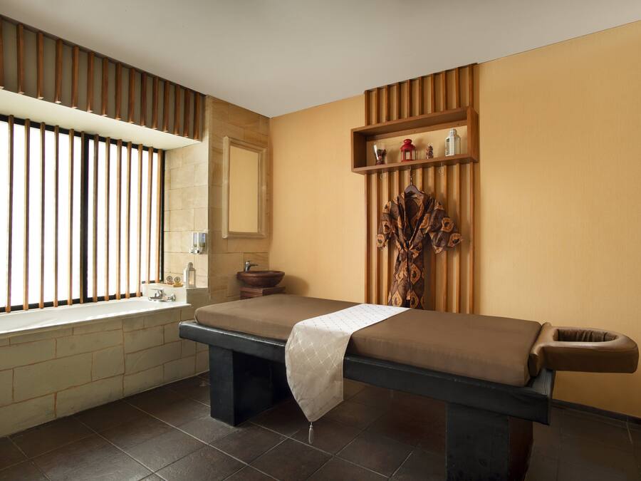 Un spa moderno con una camilla de masaje, un ventanal con persianas verticales, un lavabo y una estantería con adornos.