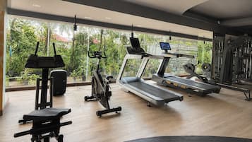Une salle de sport équipée de tapis de course, de vélos d’exercice et d’appareils de musculation.