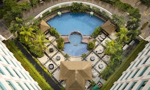 An aerial view of a hotel with a central swimming pool surrounded by lounge areas and greenery. - Hotel Ciputra Jakarta (Jakarta)