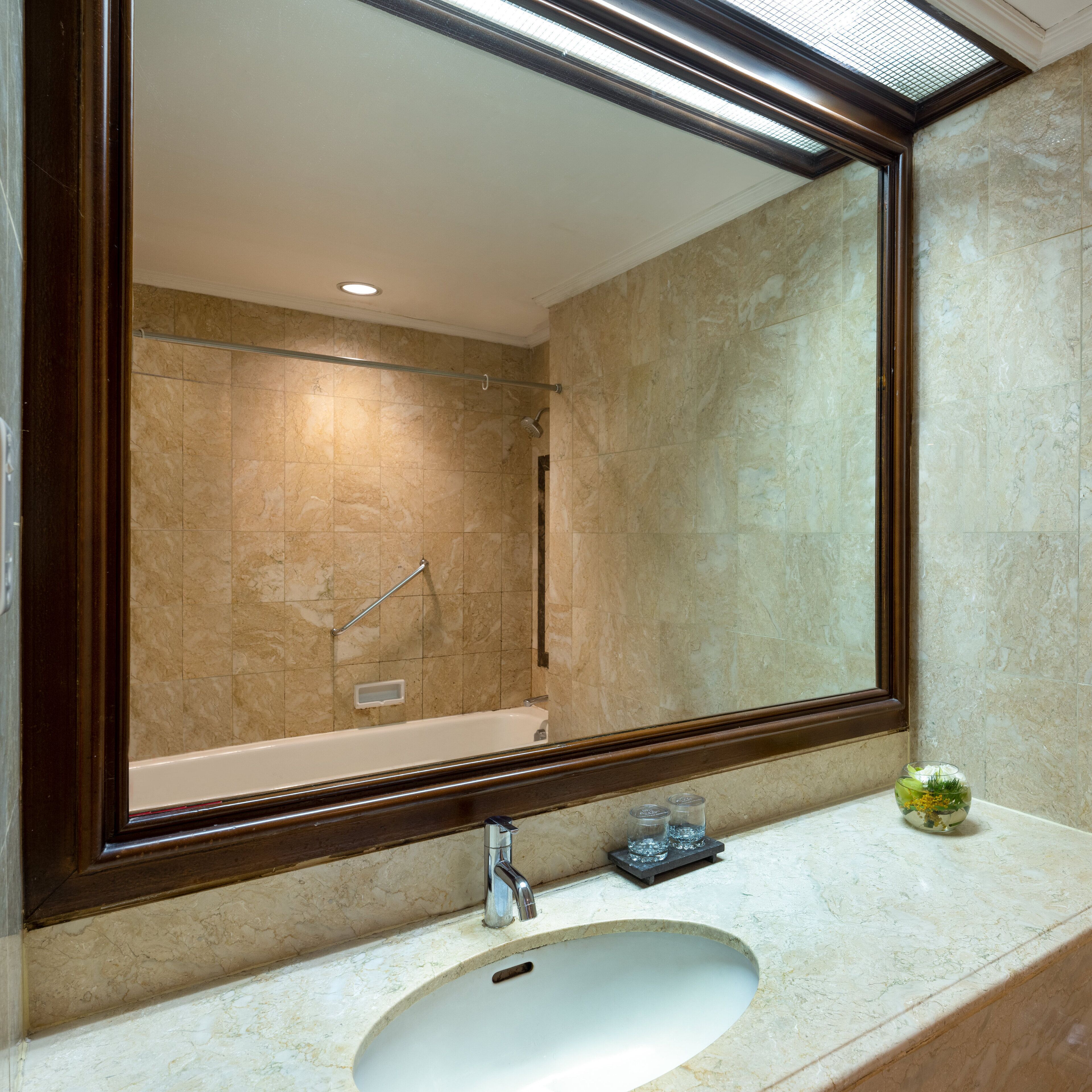 A bathroom with a large mirror, a bathtub, and a sink.
