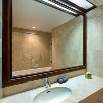 A bathroom with a large mirror, a bathtub, and a sink.