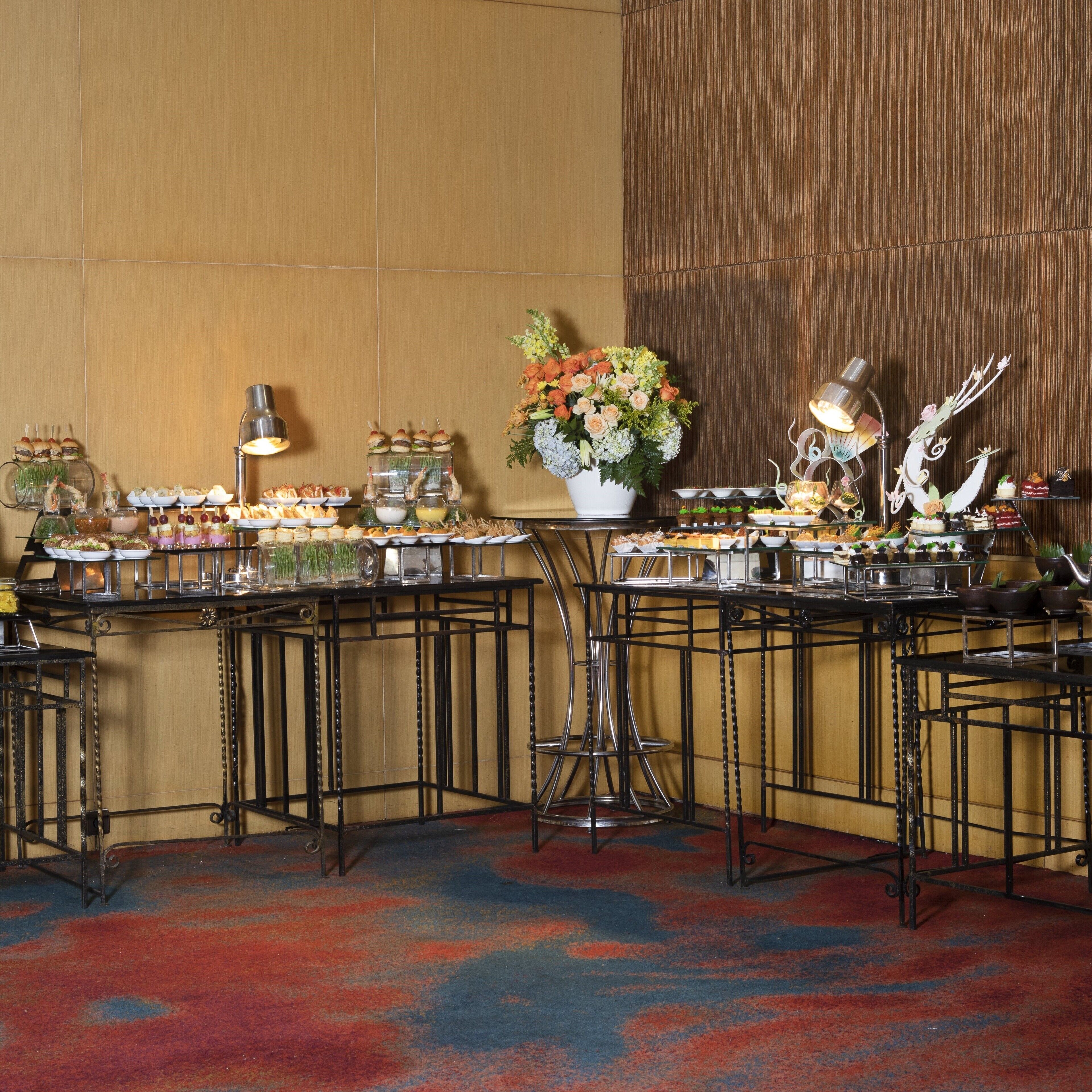 A buffet setup with various food items and a floral centerpiece.