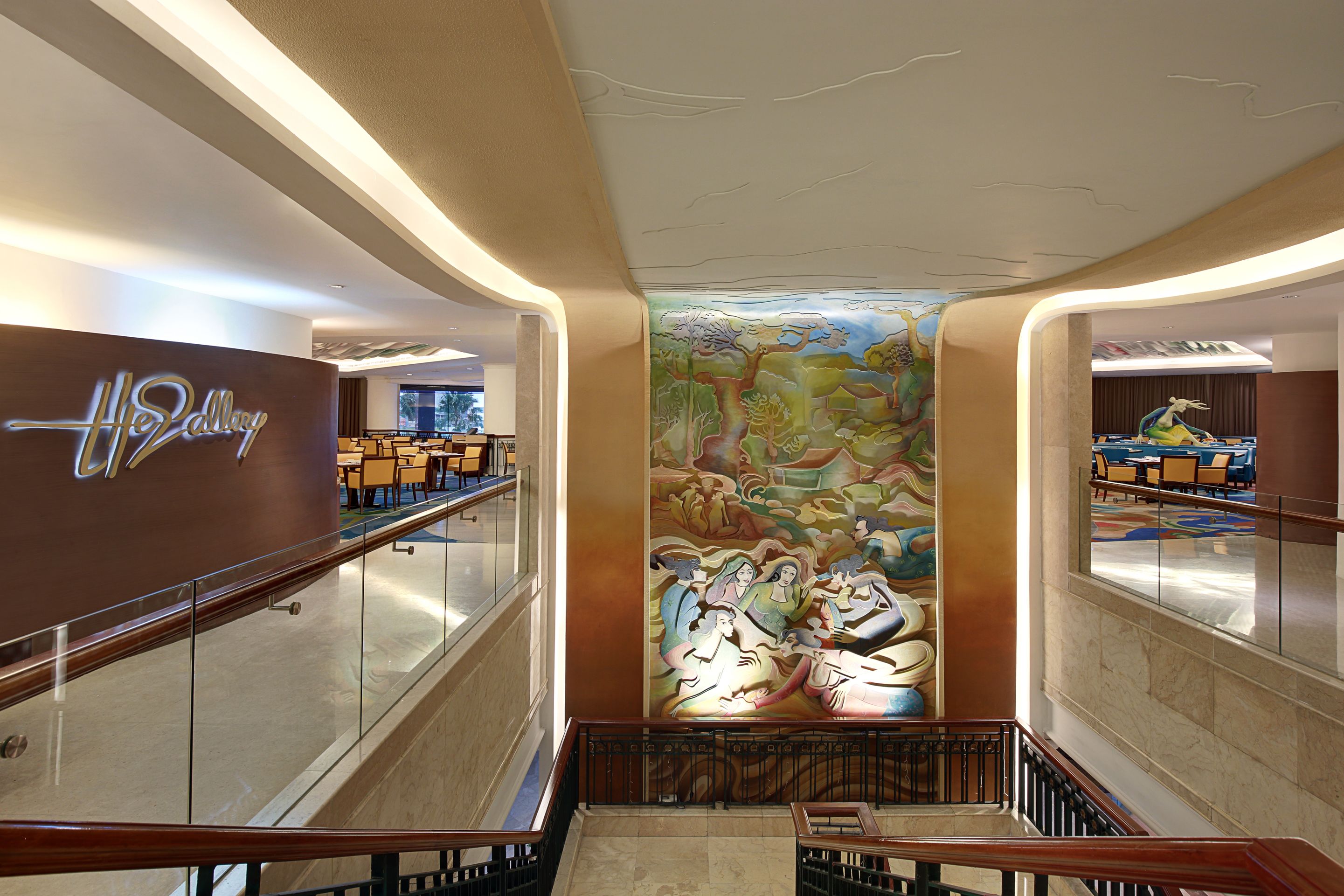 A hotel lobby with a central mural, a reception desk, and seating areas.