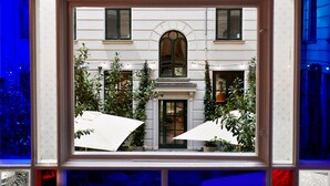 A building with a white facade, arched windows, and a central door. There are potted plants and umbrellas outside. - Coco Hotel (Copenhagen)