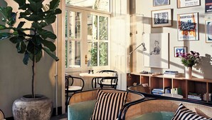 A cozy seating area with cushioned chairs and a table, a large potted plant, and artwork on the walls. - Coco Hotel (Copenhagen)