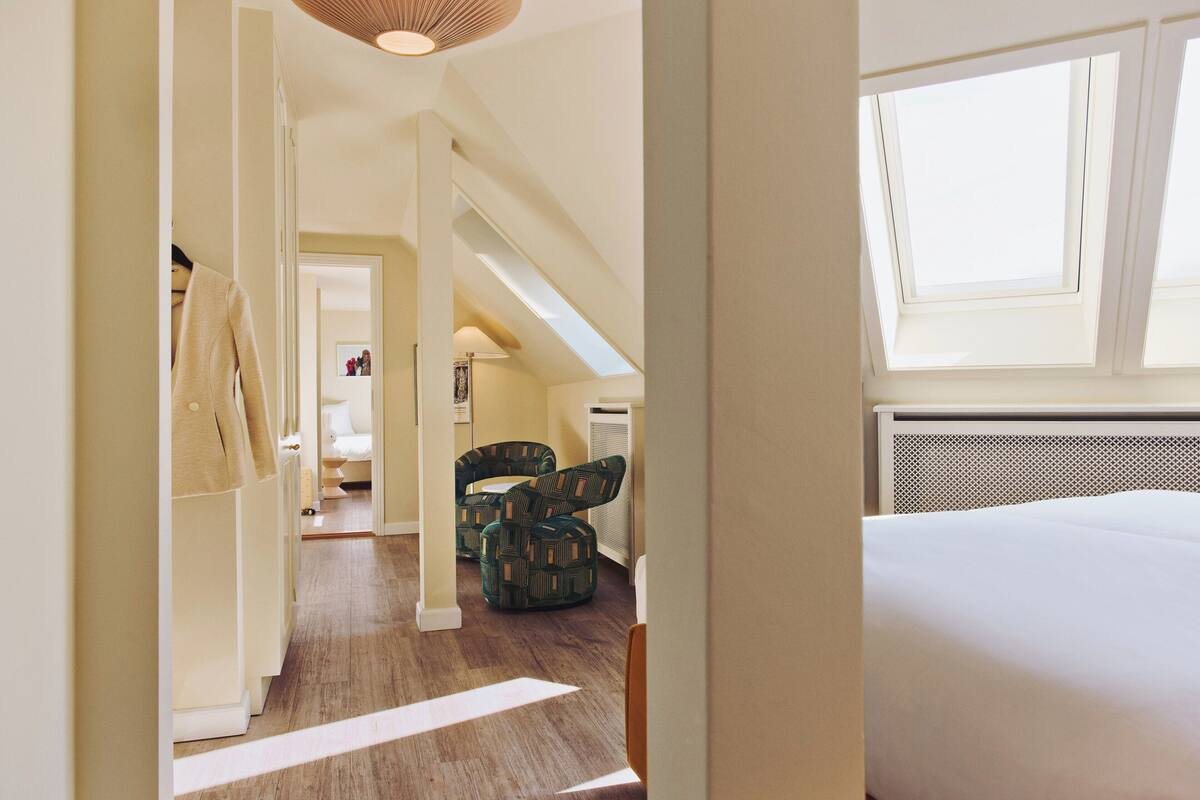 A bedroom with a bed, a skylight, and a view of a hallway.