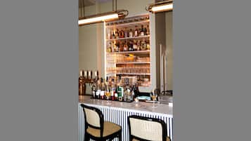 A bar area with a wine rack, shelves of bottles, and two wicker chairs.
