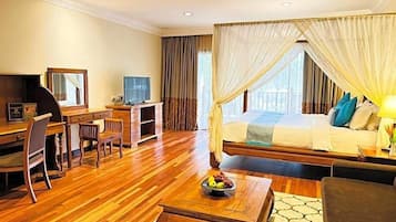 A hotel room with a bed, a desk, a chair, a television, and a fruit bowl.