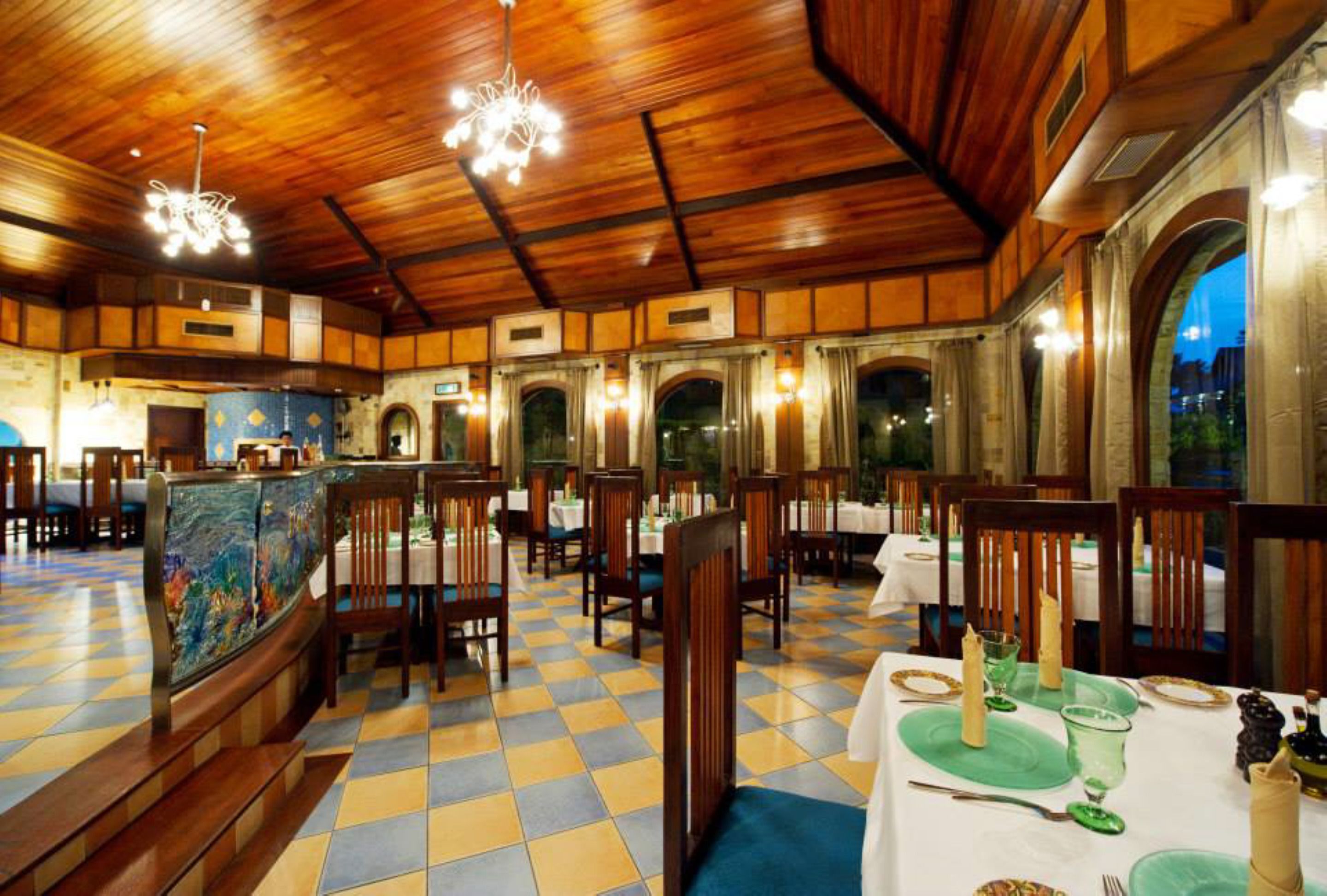 A restaurant with wooden paneling, checkered flooring, and tables set for dining.