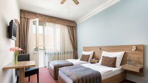 Habitación de hotel con dos camas, un escritorio, una silla, un televisor y una ventana con cortinas.