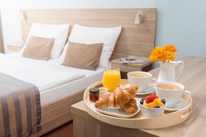 A neatly made breakfast tray with croissants, fruit, coffee, and juice on a hotel room table. - Art Hotel Meda of Museum Kampa (Prague)