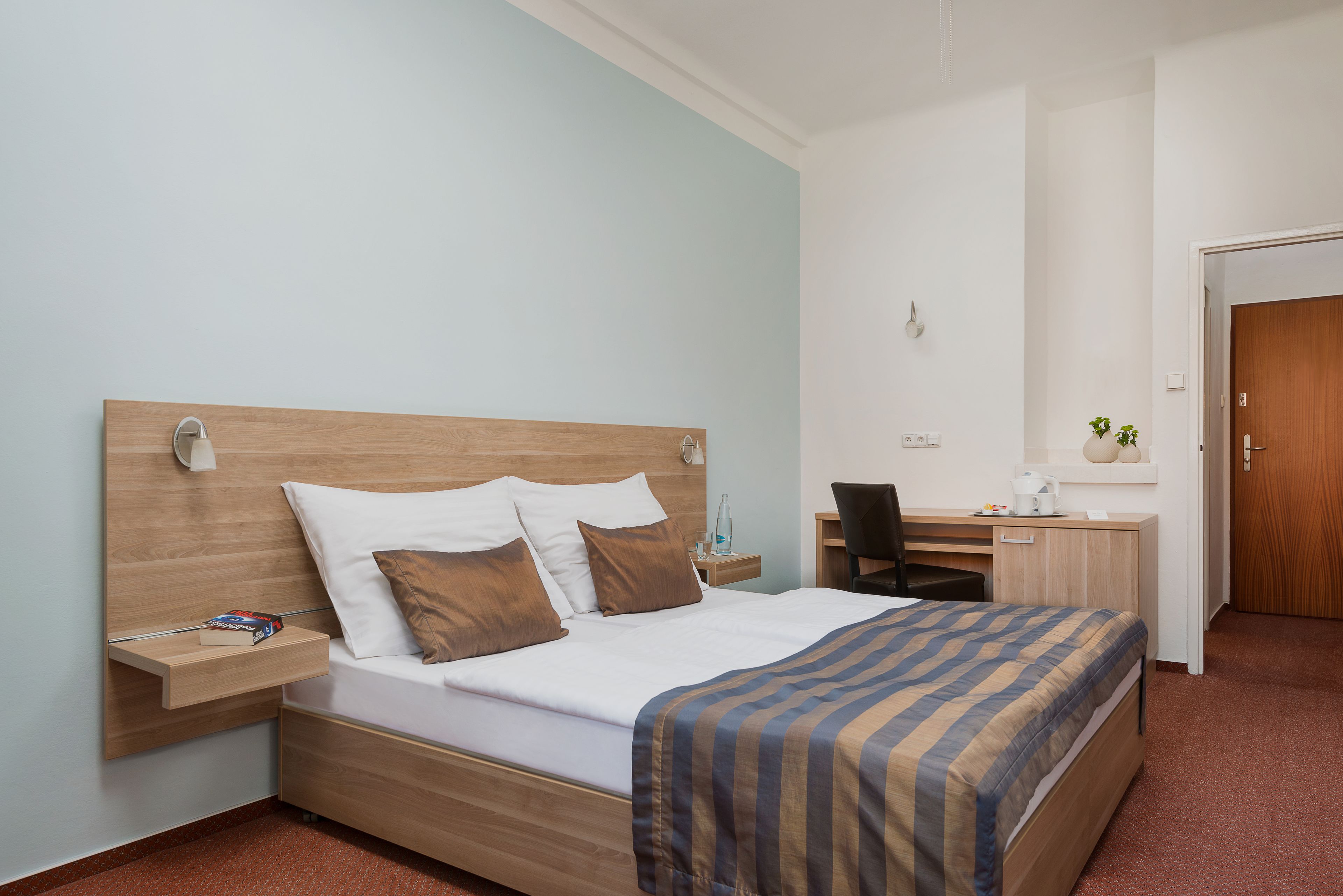 A hotel room with a wooden bed, a desk, and a chair.