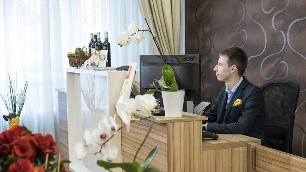 Una mesa de recepción con una computadora, una planta y un florero.