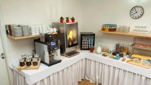 Una barra de desayuno con máquinas de café, un refrigerador y diversos alimentos.