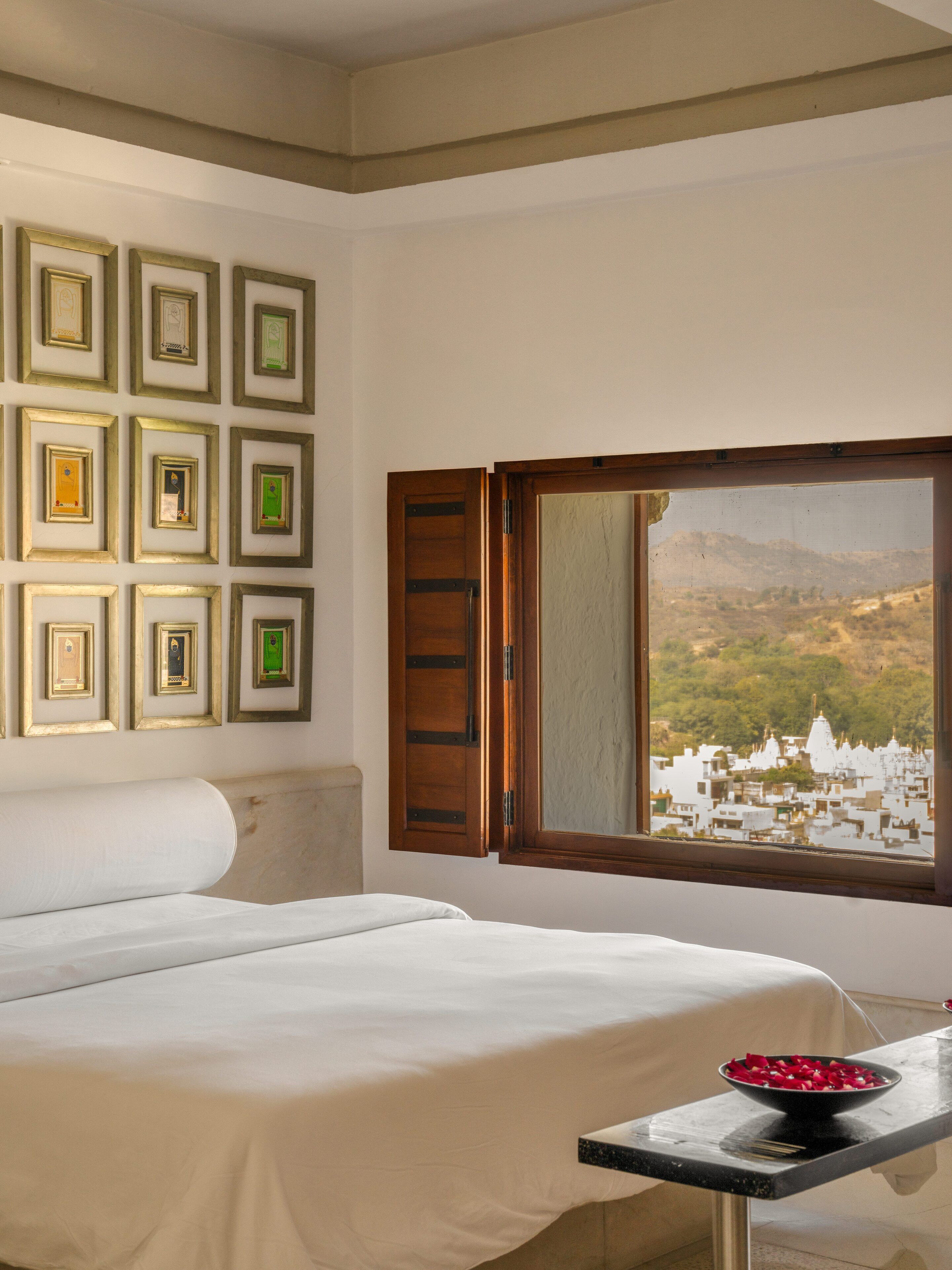 Ein Hotelzimmer mit einem Bett, einem Tisch mit Obstschale und einer Wand mit gerahmten Bildern.