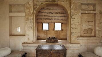 Traditional room with a stone wall, wooden chest, and two windows.