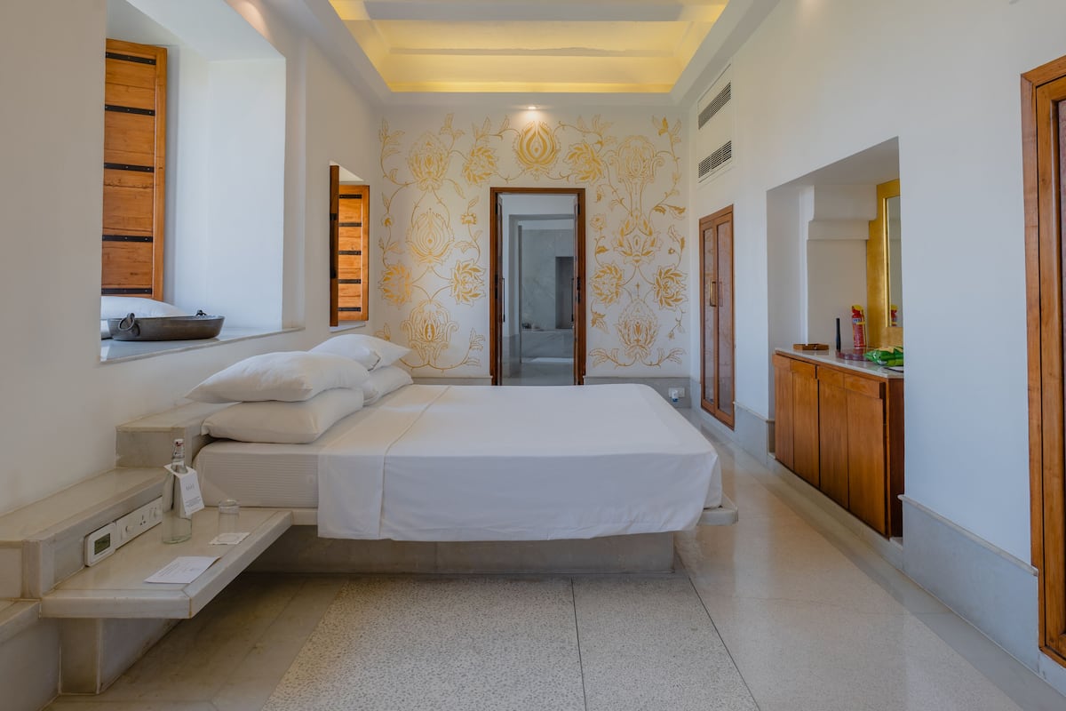 A modern bedroom with a bed, bedside table, and a window with a view.