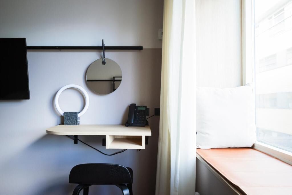 A compact workspace with a desk, chair, and a round mirror.