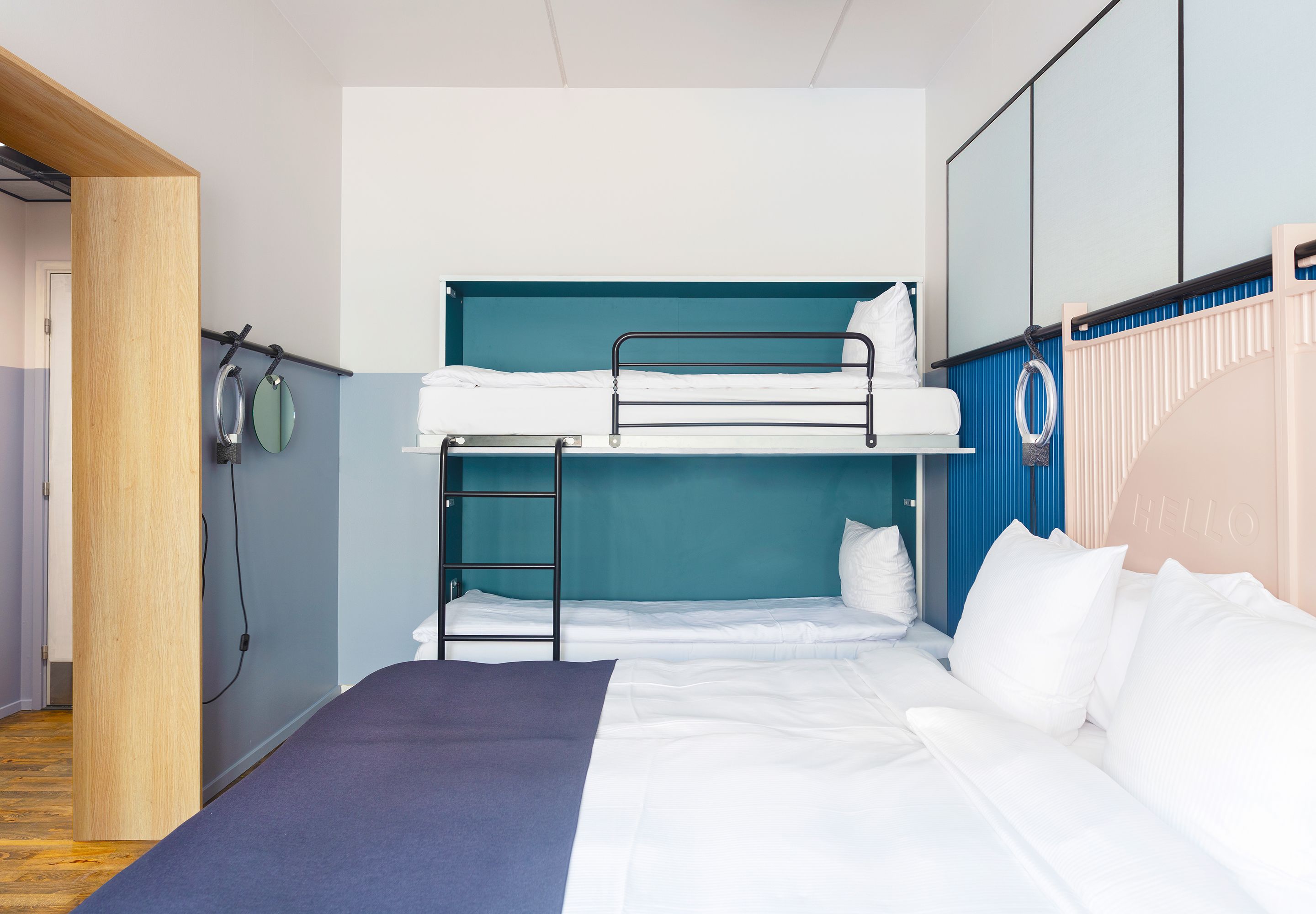 Une chambre avec un lit superposé, une tête de lit bleue, une échelle et un matelas blanc.