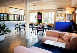 Un hall d’hôtel comprenant des espaces de détente, un bar et un comptoir d’accueil.