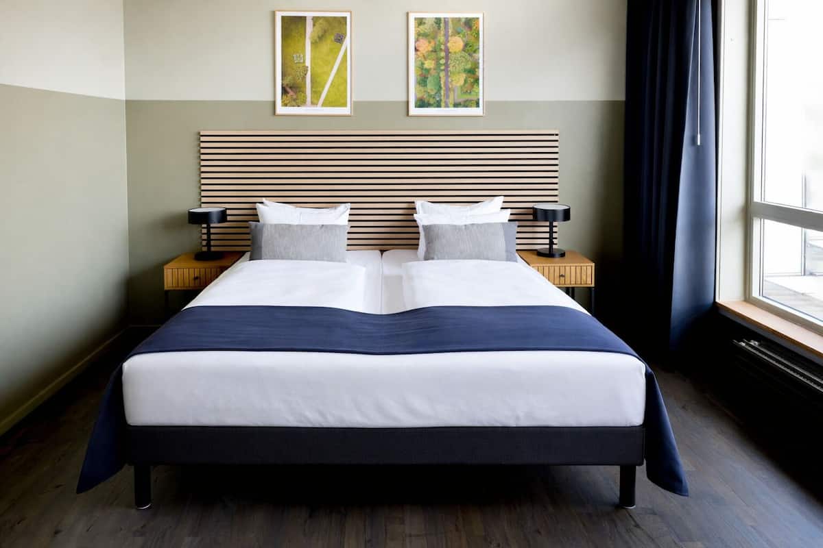A large bed with a wooden headboard, two bedside tables, and artwork on the wall.