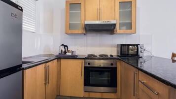Una cucina con mobili in legno, un frigorifero in acciaio inossidabile, un forno a microonde e un fornello.