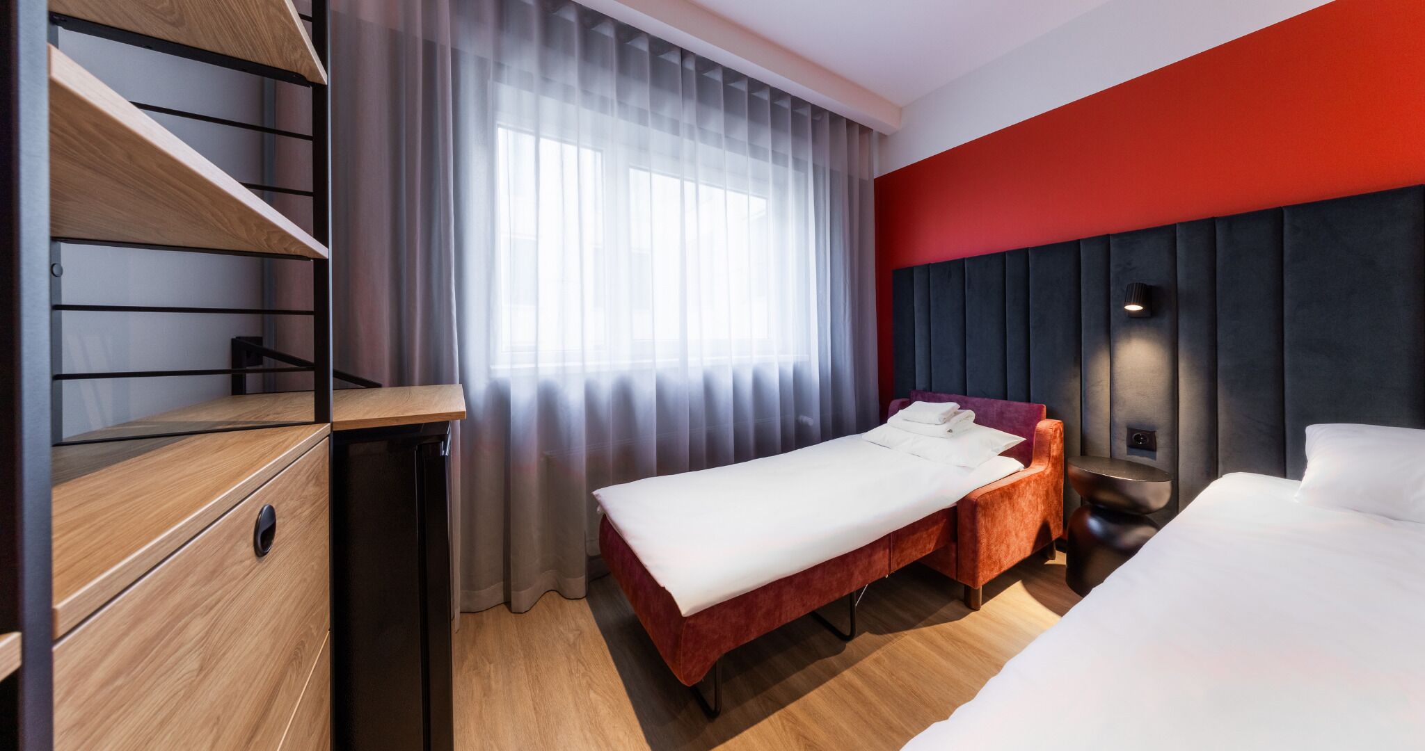 Une chambre d’hôtel avec un lit, un bureau et une armoire.