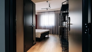 Un dormitorio con cama, armario, escalera y ventana con cortinas.