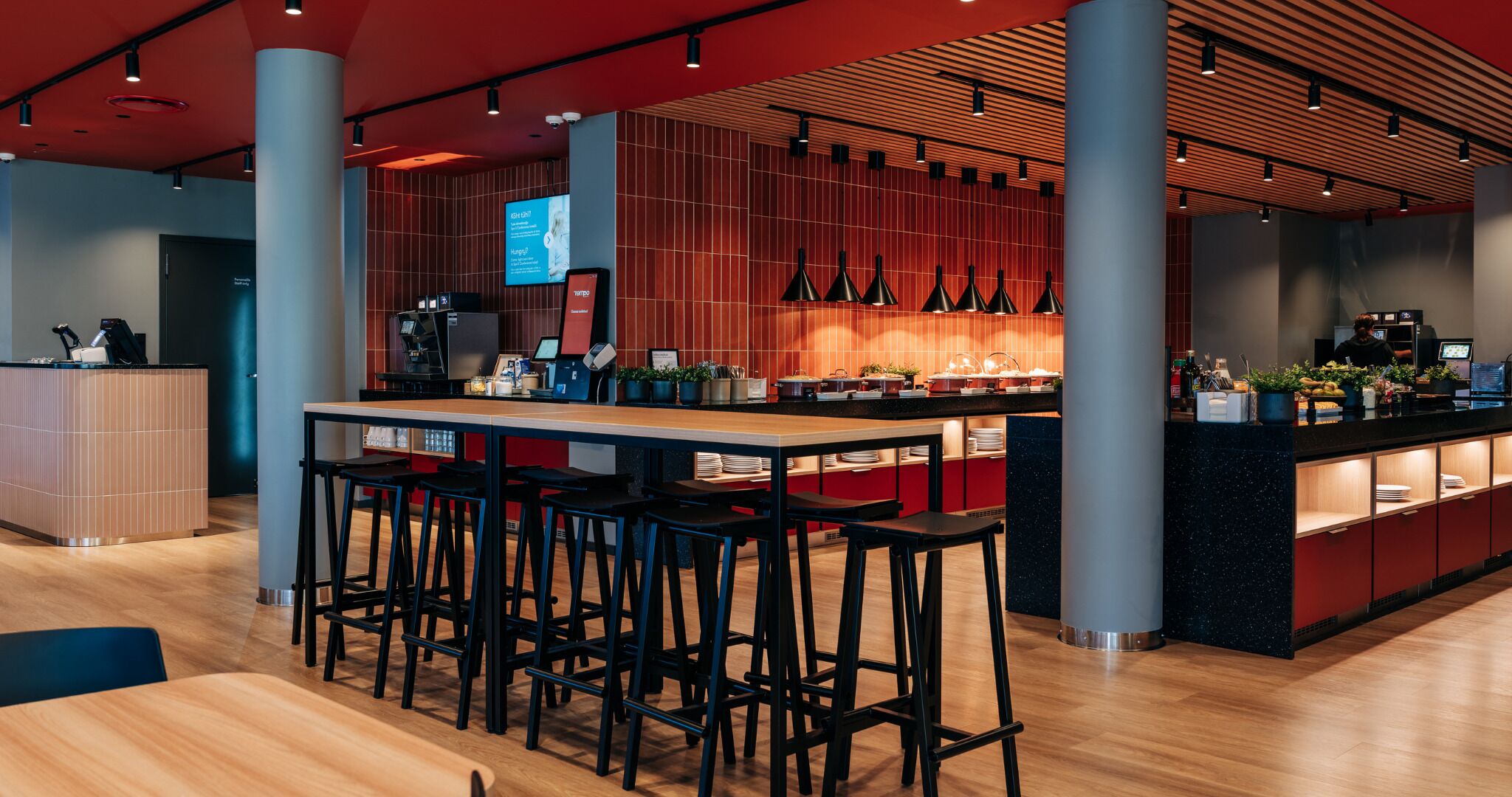 A modern bar area with stools, a counter, and a digital menu display.
