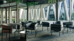 Un área de estar interior moderna con paredes de vidrio, muebles contemporáneos y vistas al exterior.