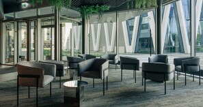 A modern indoor seating area with glass walls, contemporary furniture, and a view of the outside.