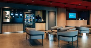 A modern hotel lobby with seating, a minibar, a coffee machine, and a digital screen displaying 'Tallink Hotels Express'. - Tallink Express Hotel (Tallinn)