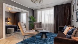 A modern living room with a sofa, armchairs, a coffee table, and a large window with curtains.