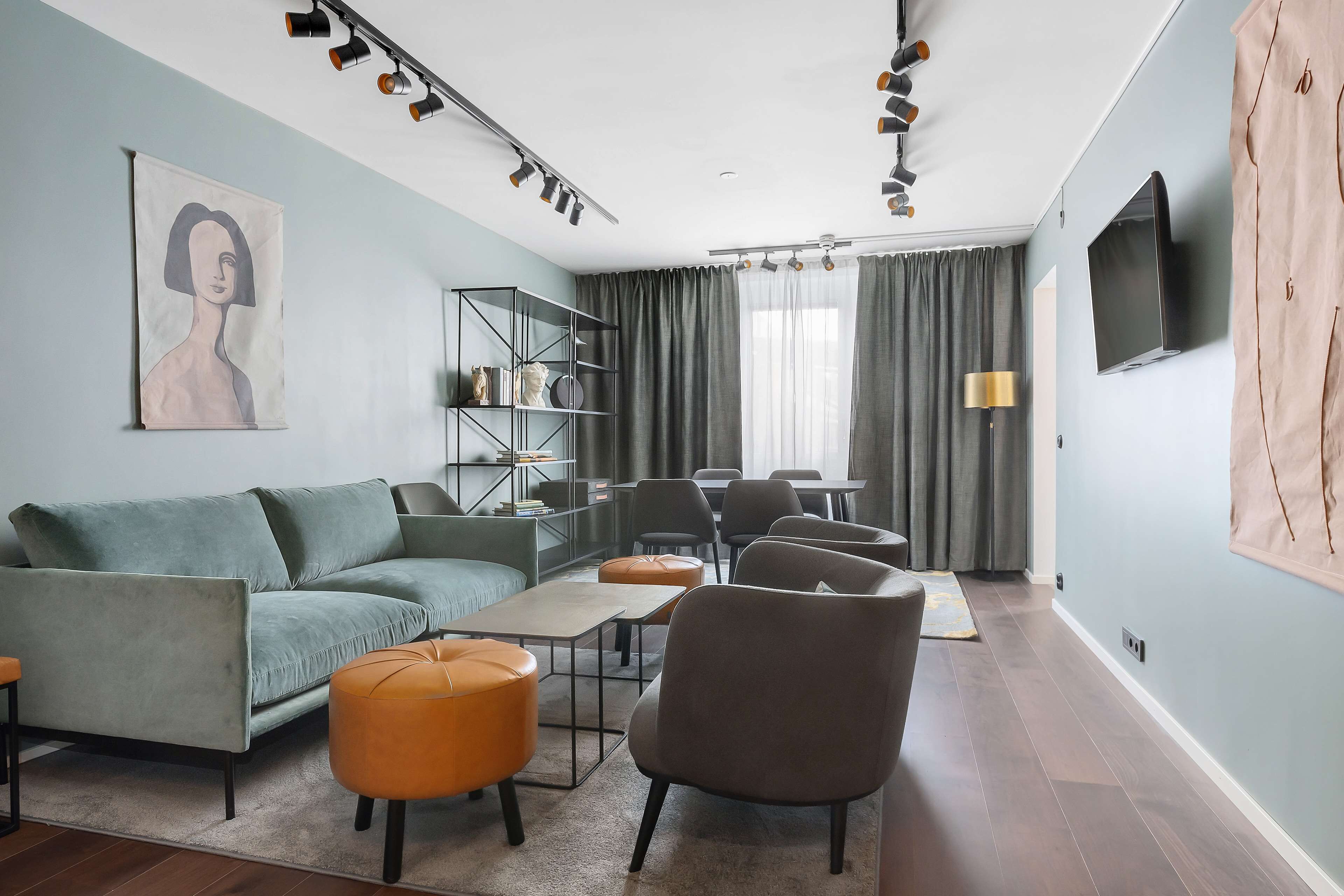 A modern living room with a sofa, ottoman, chairs, a coffee table, and a TV.