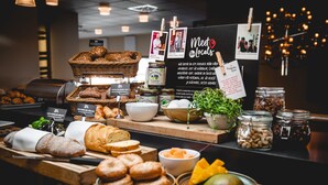 A bakery display with various breads, pastries, and jars of nuts.