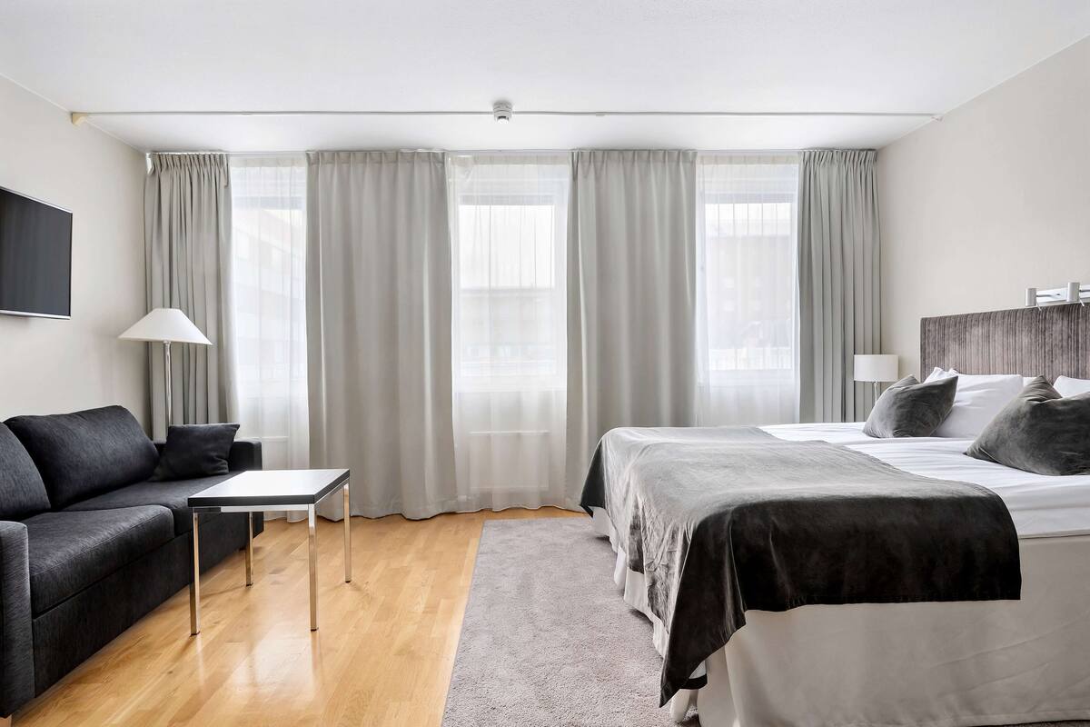 Une chambre d’hôtel moderne équipée d’un lit, d’un canapé, d’une petite table et d’un téléviseur.