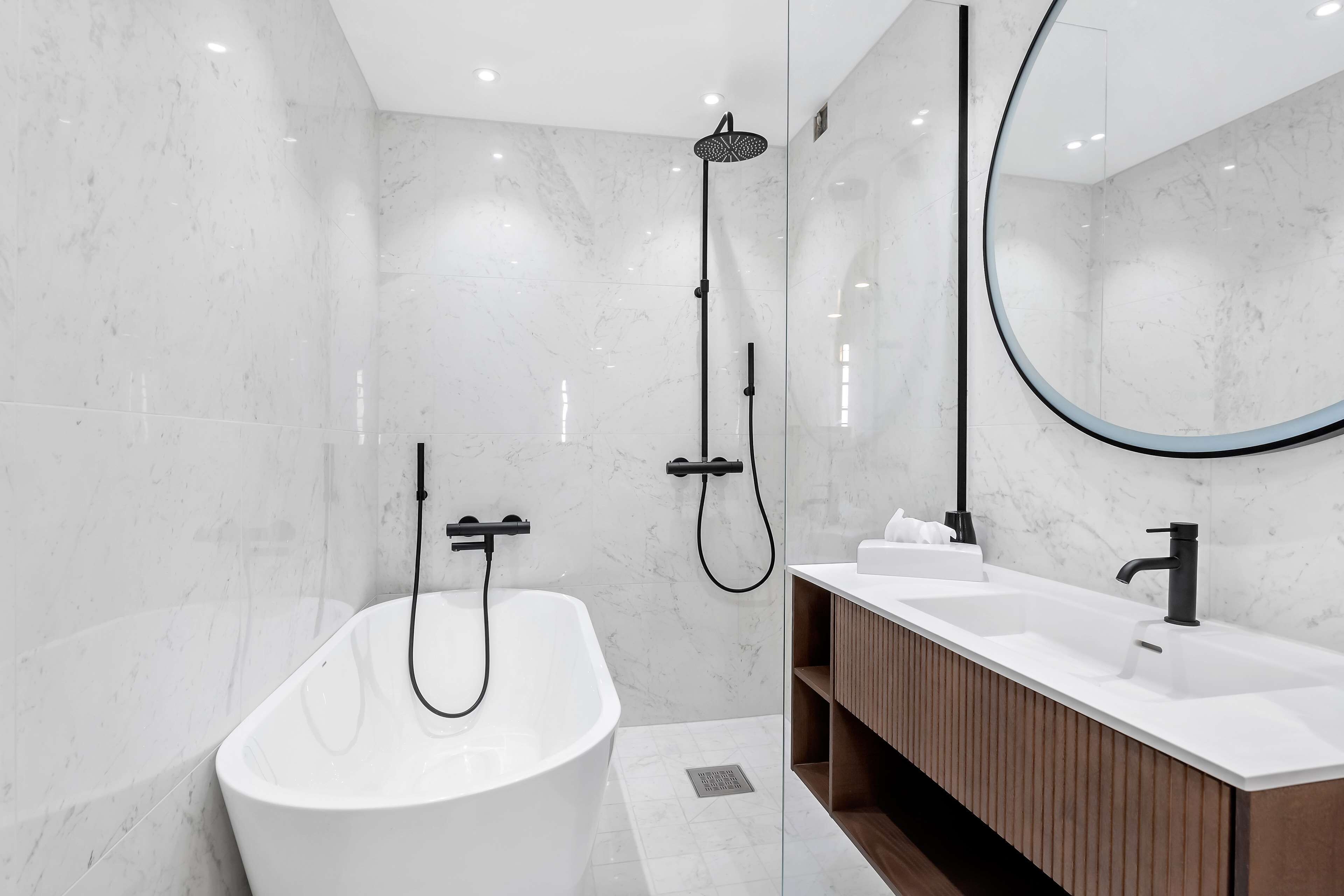 A modern bathroom with a freestanding bathtub, a walk-in shower, and a vanity with a mirror.