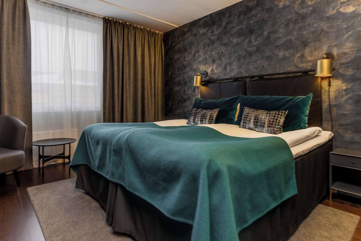 Une chambre moderne avec un grand lit, une tête de lit sombre et deux lampes de chevet.